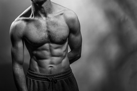 A young male body with well-defined abs and chest. Model with shirtless torso. Concept of body care, male health, fitness, youth, masculinity, health, weightloss, bodybuildingの写真素材