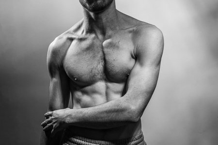A young male body with well-defined abs and chest. Model with shirtless torso. Concept of body care, male health, fitness, youth, masculinity, health, weightloss, bodybuildingの写真素材