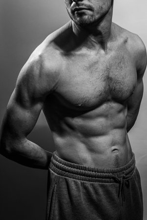 A young male body with well-defined abs and chest. Model with shirtless torso. Concept of body care, male health, fitness, youth, masculinity, health, weightloss, bodybuildingの写真素材