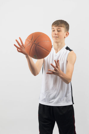 Fifteen year old teenage boy catching a basketball, studio shot against a white backgroundの写真素材