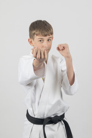 Fifteen year old male teenage karate black belt doing a Uraken Uchi, studio shot against a white backgroundの写真素材