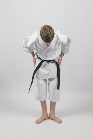Fifteen year old male teenage karate black belt bowing, studio shot against a white backgroundの写真素材
