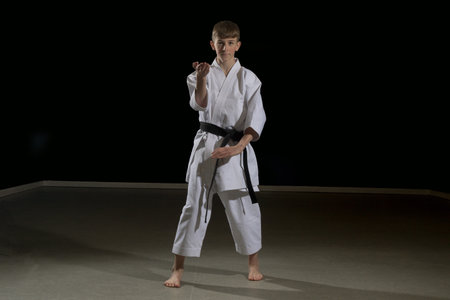 Fifteen year old male teenage karate black belt performing kata Kururunfa, studio shot against a black backgroundの写真素材