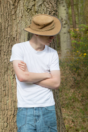 Teenage boy wearing a hat, white t-shirt and blue denim. With his arms foldedの写真素材