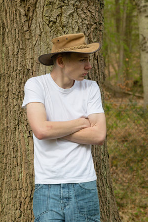 Teenage boy wearing a bush hat, white t-shirt and blue denim. With his arms foldedの写真素材