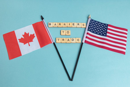 The Flags of The United States and Canada trade war concept, with tiles reading Barriers To Tradeの写真素材
