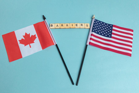 The Flags of The United States and Canada trade war concept, with tiles reading Barriersの写真素材