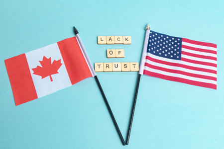 The Flags of The United States and Canada trade war concept, with tiles reading Lack Of Trustの写真素材