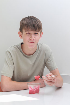 Teenage boy eating pre sliced, store bought water melon with a forkの写真素材