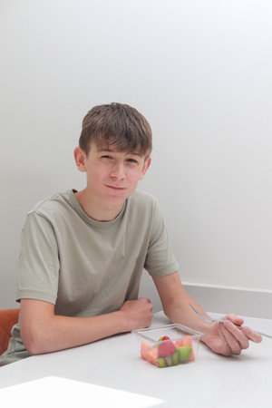Teenage boy eating freshly prepared, store bought fruit,  with a forkの写真素材