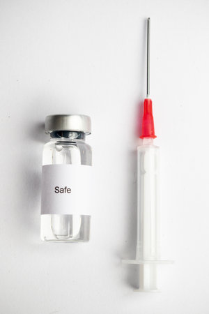 Vaccine concept, an Isolated medical vial with a label reading Safe and a syringe on a plain white background.の写真素材
