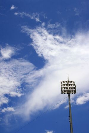 Blue sky and white clouds and a stadium spot light post at right hand corner.の写真素材