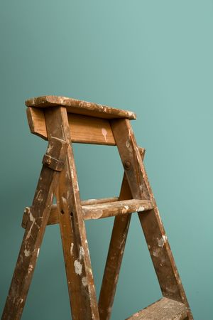 An old rustic ladder standing against a green wallの写真素材