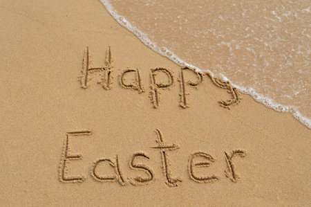 Happy Easter written written in the sand at the beach and washed away by wavesの写真素材