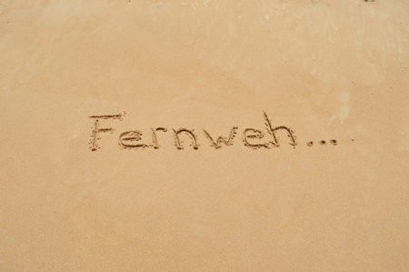 The german word 'Fernweh' (which means wanderlust) written in the sand at the beachの写真素材