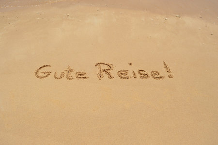 The German phrase 'Gute Reise' (translated: Have a good trip) written in the sand at the beachの写真素材