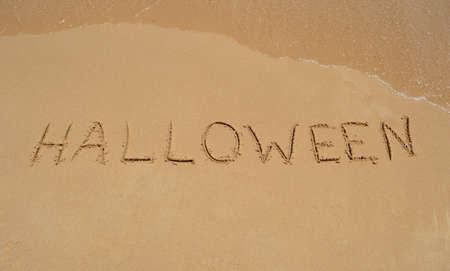 The word 'Halloween' written in the sand at the beachの写真素材