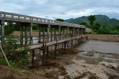 Old bamboo bridge and new bridge made of concrete crossing a river in northern Thailand.の写真素材