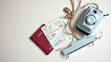 Travel essentials with passport, boarding pass, camera, and sunglasses on white background. That the image is generated using AI.の素材