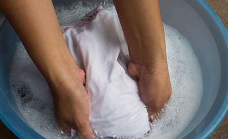 Hand washing clothes in the basin blue.の写真素材