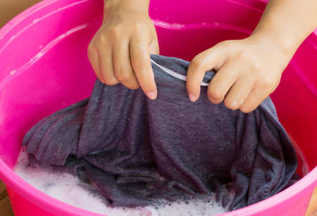 Hand washing clothes in the basin blue.の写真素材