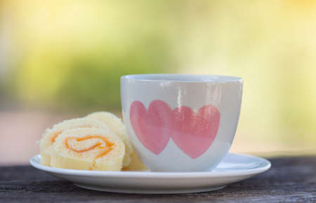 jam roll cake and a cup of hot coffee on the tableの写真素材