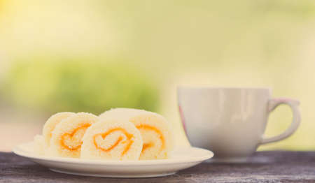 jam roll cake and a cup of hot coffee on the table.の写真素材