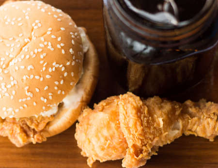 Fried chicken and burger with sparkling water on wooden plateの写真素材