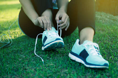 Young woman trying to lace up her sneakersの写真素材