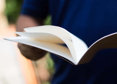 Hand holding white journal.の写真素材