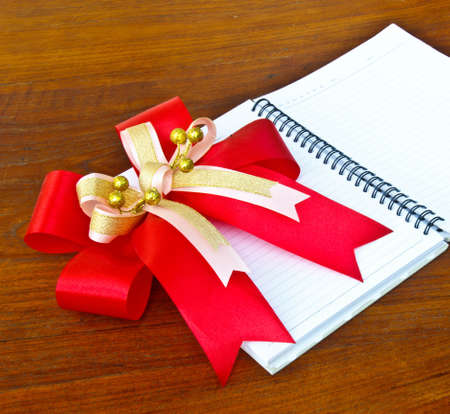 Red ribbon on the white notebook on wooden table,Beautiful and classic.の写真素材