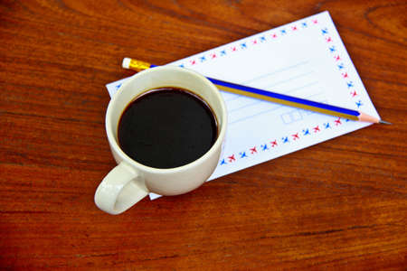 Envelope on a wooden table with a pencil and coffee,Beautiful and classic.の写真素材