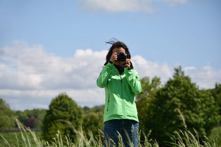 Beautiful asian woman taking a picture with a cameraの写真素材