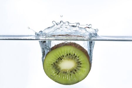 A piece of Kiwi falling in waterの写真素材