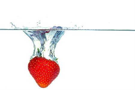 Red strawberry falling into water with a splashの写真素材