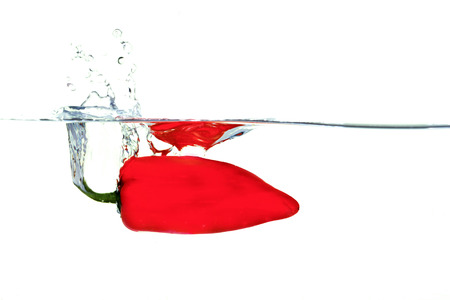 Red pepper falling into water with a splashの写真素材
