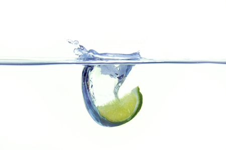Green lemon falling into water with a splashの写真素材