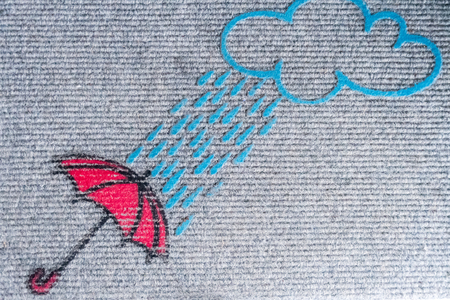 picture of a doormat showing a red umblella and a raining cloudの写真素材