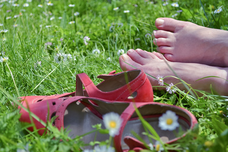 Barefoot woman with red shoes relaxing on a meadowの写真素材