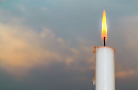 Closeup of burning candle on dark sky backgroundの写真素材