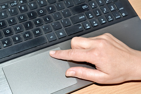 A hand of a woman working on an old laptopの写真素材
