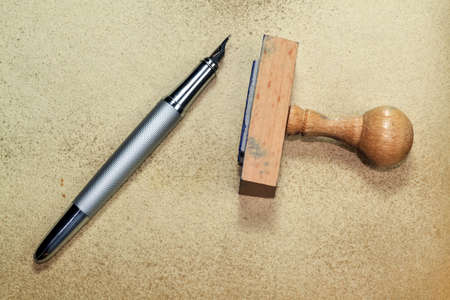 Wooden rubber stamp and inky pen on grungy backgroundの写真素材