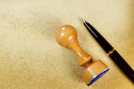 Wooden rubber stamp and inky pen on grungy backgroundの写真素材