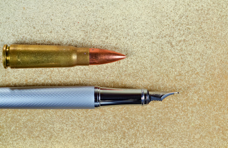 Pen and a bullet arranged horizontally on vintage backgroundの写真素材