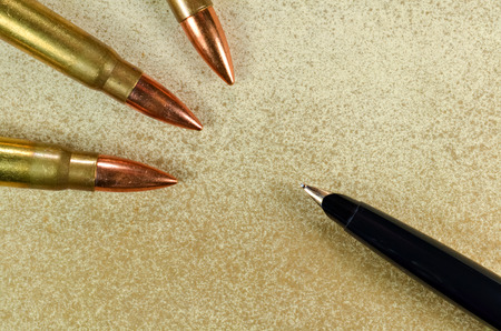 Black fountain pen and three bullets arranged in the corners of the imageの写真素材