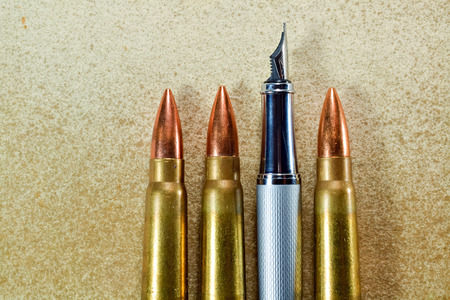 Pen and three bullets arranged verticaly on vintage backgroundの写真素材