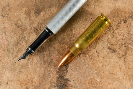 Fountain pen and a bullet in a parallel position on vintage backgroundの写真素材