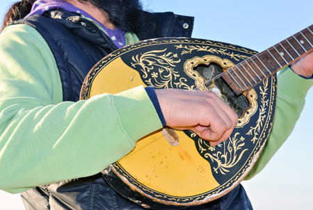 Street music entertainer playing mandolin with two stringsの写真素材
