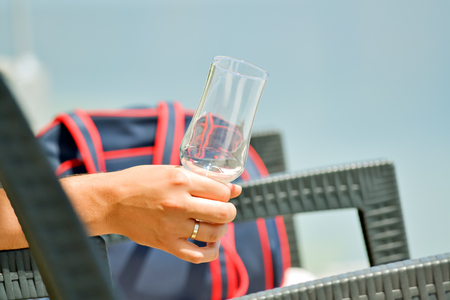 Closeup of the hand of a tourist on the beach holding an empty glassの写真素材