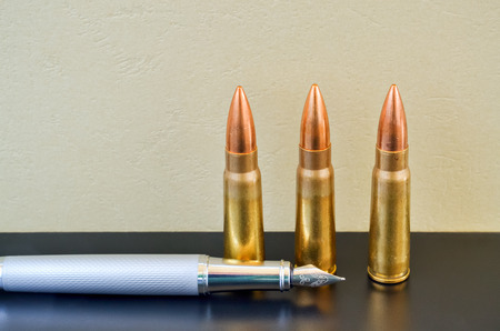 Pen and bullets as a preference of words instead of violenceの写真素材